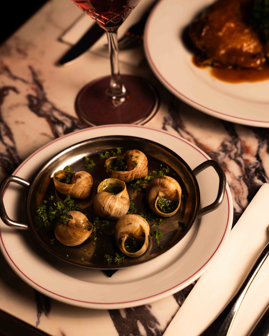 Escargots de Bourgogne et verre de vin rouge sur une table en marbre