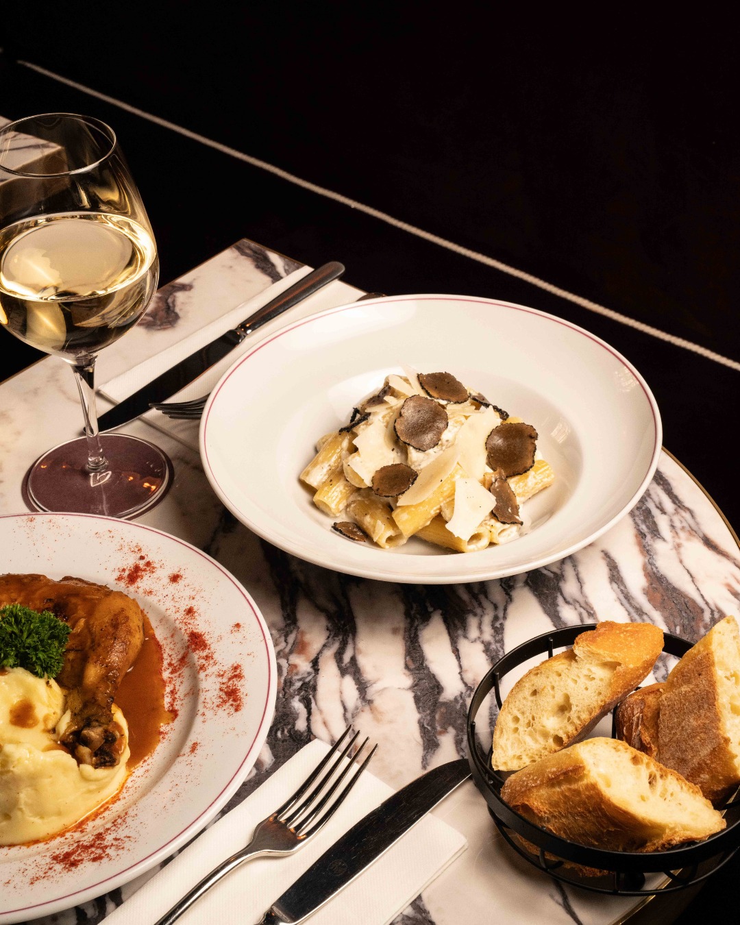 Table gourmande dressée avec des plats français et un verre de vin blanc
